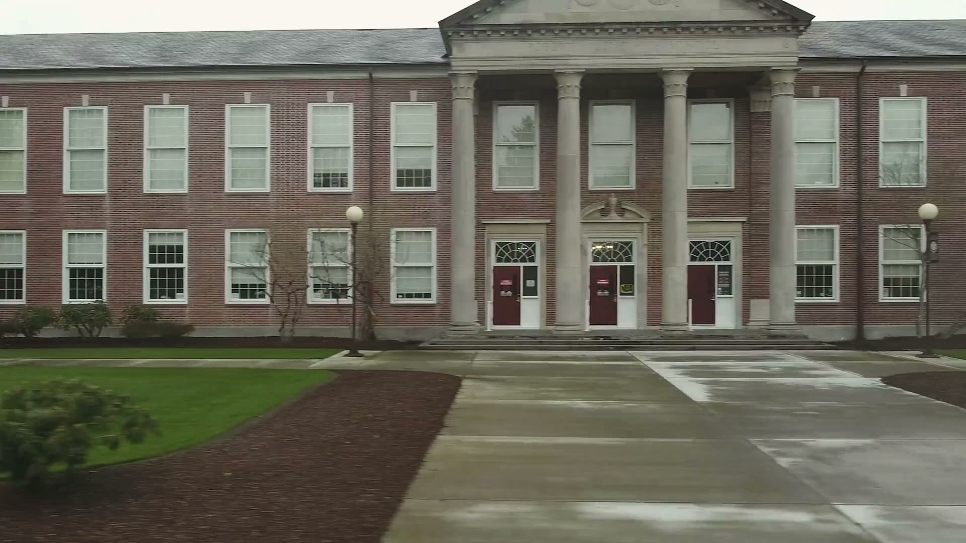 The front of a brick high school with white columns.